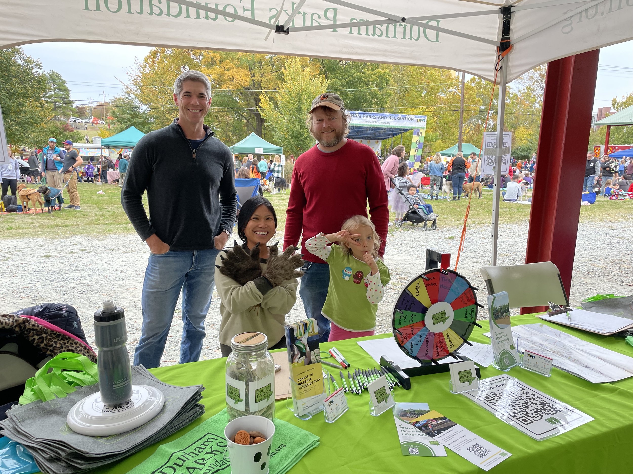 Durham Parks Foundation President, David Greene, and Board Members, Ryan Mentock and Farrah Sangsookwow Shapiro, at Barktoberfest in Durham Central Park.